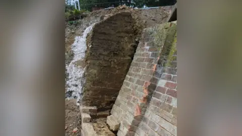 HSE Image of a collapsed brick wall along a canal path