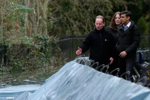 Getty Images Rishi Sunak being shown flood defences