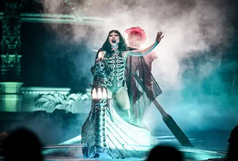 Getty Images Lady Gaga sings on stage at the O2 Arena in a gothic bodice, with her hand on a prop skull