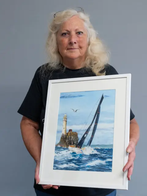 Jim Grover Su Hillman with her painting of a boat at sea
