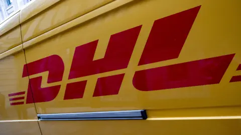 A red "DHL" sign on the side of a yellow van. 