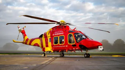A red and yellow helicopter parked on tarmac.