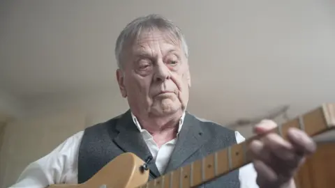 Ian Horne playing a guitar