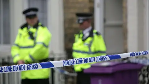 Getty Images Police officers stand outside a house in Hatherley Street, after a raid searching for terror suspects on 1 July 2007 in Liverpool, England