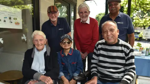 Men's Matter Sir Michael Parkinson with five other gentlemen at a summer barbeque.