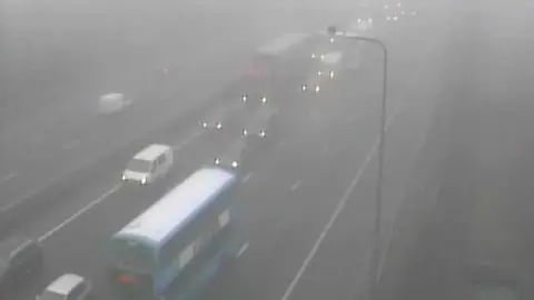 A screenshot of a Highways England traffic camera showing lots of queuing traffic on the M5 southbound. On the northbound road, there is only one van driving down one lane.