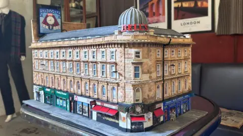 A cardboard model of Union Corner. It is a Victorian Building with colourful shop fronts on the ground floor.