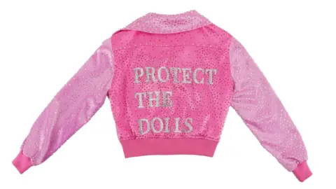 GLAAD A pink jacket. On the back of it is written: Protect the Dolls.