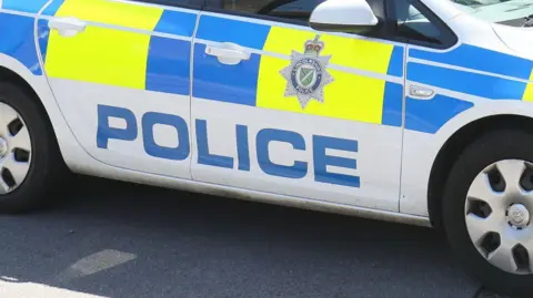 BBC A Lincolnshire Police car parked by the side of a road. It has blue and yellow markings on and the Lincolnshire Police badge.