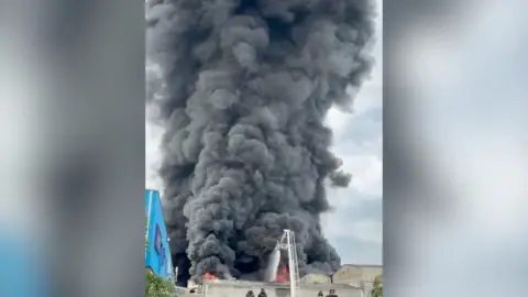 Smoke billows into the sky from an industrial estate fire.