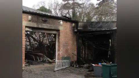 Norfolk Fire and Rescue Service The entrance to a brick industrial unit has scorch marks and the roof has collapsed, with lots of debris seen inside and another section to the right has been left blackened and the roof has collapsed.
