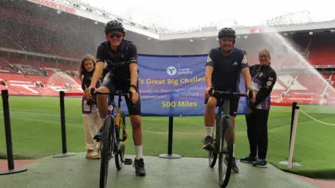 Family handout Zac and his father, James, pictured on bikes at the Old Trafford stadium in Manchester