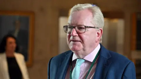 Getty Images A man with fair hair and glasses in a business suit 