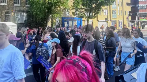 Fans huddled around other fans handing out free gifts