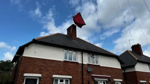 A red tent in the air above two semi-detached houses