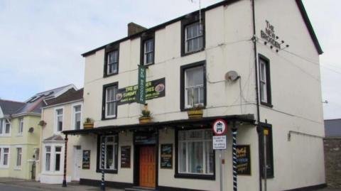 The  Brogden pub (a white building with signs for the pub)