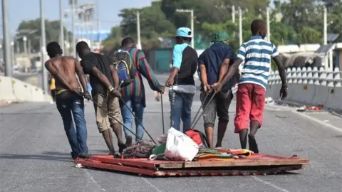 AFP Looters carry away items in Delmas, a commune near Port-au-Prince, during protests against the rising price of fuel, on July 8, 2018.