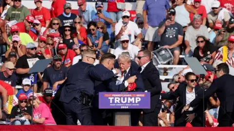 Reuters Donald Trump is shielded by Secret Service officers after shooting at rally