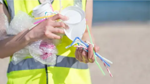 Getty Images Person collecting plastic on a beach