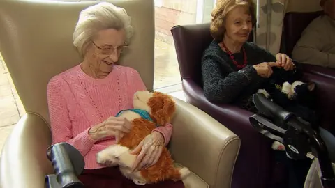 Care home residents stroking robotic pets