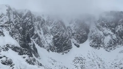 SAIS Southern Cairngorms Steep, rocky cliffs on the mountain covered in snow.
