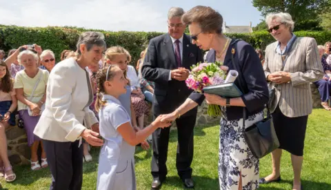 States of Guernsey The Princess Royal shakes hands with a young girl in a school uniform