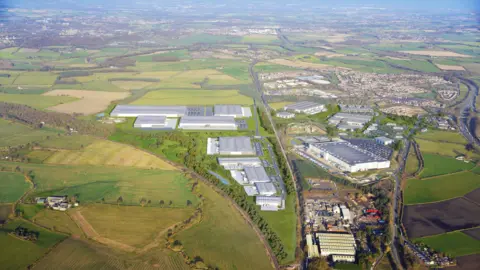 A computer generated image of the proposals shows large grey industrial units. A road separates the site from abother industrial sire and residential houses. 