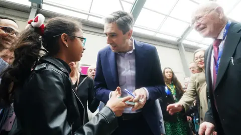 PA Media Simon Harris speaks to a young girl at the Fine Gael conference