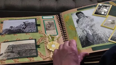 A scrap book with black and white images of Gwen thatching roofs