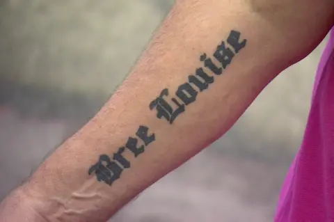 Close up of a male forearm with tattoo with Bree Louise written upon it in gothic writing