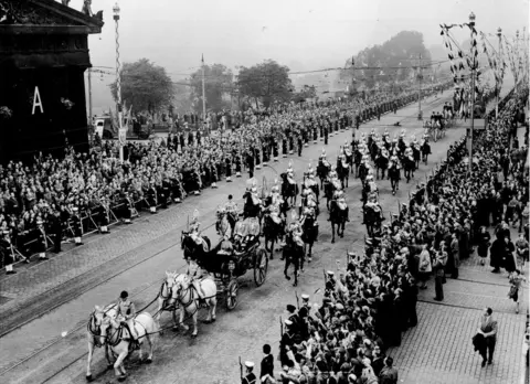 Alamy The Queen and Prince Philip ride in a carriage along Princes Street while people line both sides of the road