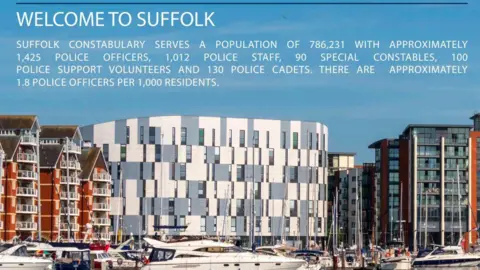 Suffolk Police and Crime Commissioner A page from a job advert, describing the population of Suffolk and the policing resources in the county. There is a picture of a large grey and white building, with apartment blocks either side and boats in the foreground. The white wording is written on top of blue sky at the top of the picture.  