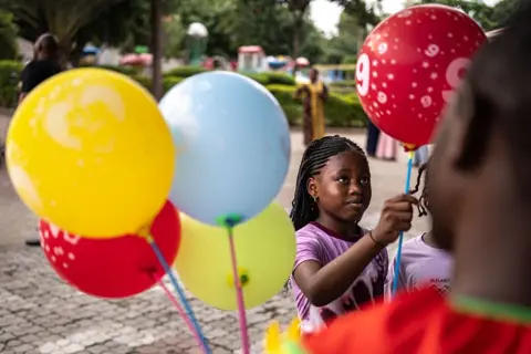 OLYMPIA DE MAISMONT / AFP / GETTY IMAGES A child picks a red balloon from a vendor at Magic Land amusement park in Abuja on 29 June.