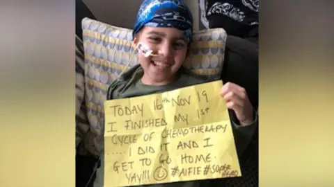 Children with Cancer UK A young boy with a breathing tube in his nose and a blue cartoon design hat is sitting in a chair holding a yellow piece of paper that reads Today 16th Nov 19 I finished my 1st cycle of chemotherapy...I did it and I get to go home yay!!!