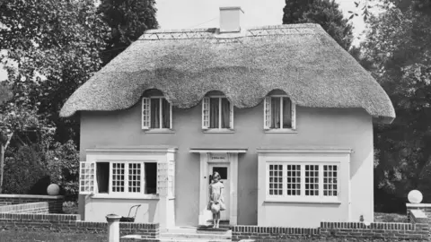 Getty Images A young Princess Elizabeth stands outside a cottage that is small enough to make her look adult sized.