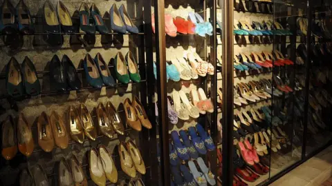 Getty Images Rows of colourful high heeled shoes being displayed behind clear glass cabinets