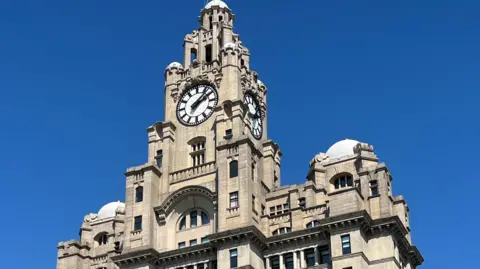 Close up of the clock of Liverpool's Royal Liver Building against a blue sky