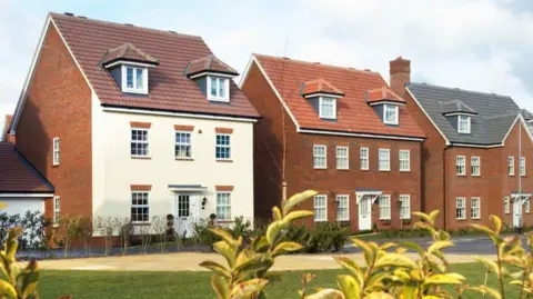 Getty Images New build detached houses built out of red brick with a grassy lawn in front