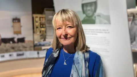Shona Sinclair is standing next a display inside the museum.