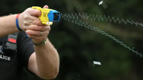 Generic image of police officer demonstrating use of a Taser