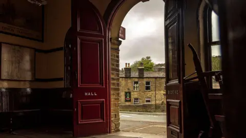 Keighley and Worth Valley Railway Red railway hall doors open to show a york stone pub across the road.
