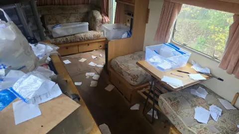 Avon and Somerset Police The inside of a caravan with Ziplock bags strewn everywhere and papers on the floor. There are also a few white plastic boxers with the Ziplock bags in.