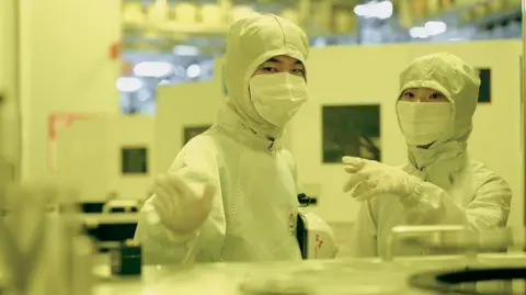 SK Hynix Employees of SK Hynix in discussion while dressed in white protective gear in a clean room 