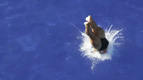 Getty Images A swimmer diving into water