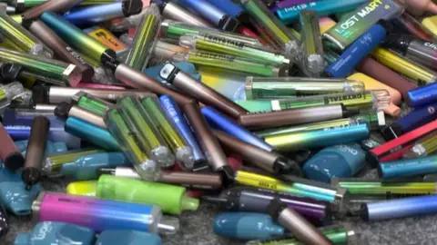 A pile of different coloured and different style vapes 