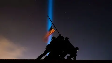 Getty Images Pillars of light illuminate the sky behind the United States Marine Corps War Memorial, on the eve of the Inauguration of President-elect Joe Biden, the United States 46th president, on Tuesday, January 19, 2021, in Arlington, VA