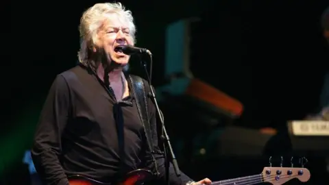 Moody Blues singer John Lodge dies aged 82 6 Harry Herd/Getty Images A man with white hair is singing into a microphone and holding a guitar.