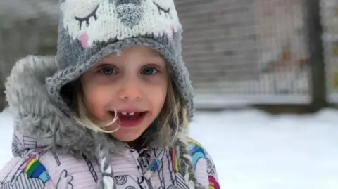 PA Media Amelia was pictured smiling at the camera - she wore a grey woolly hat with an animal face design and a bright winter coat. There was snow in the background.