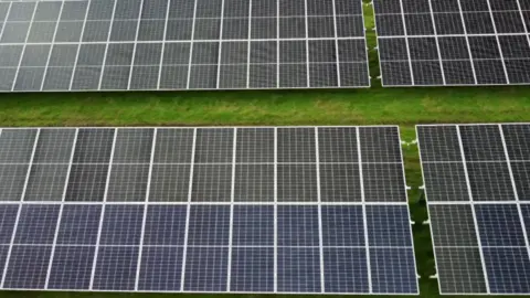 A field filled with black solar panels arranged in a grid pattern.