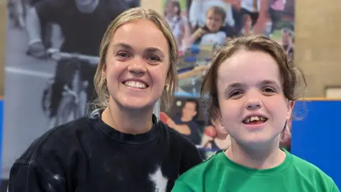 Matthew York Paralympic swimmer Ellie Simmonds and young swimmer Sohpie York smiling at the camera